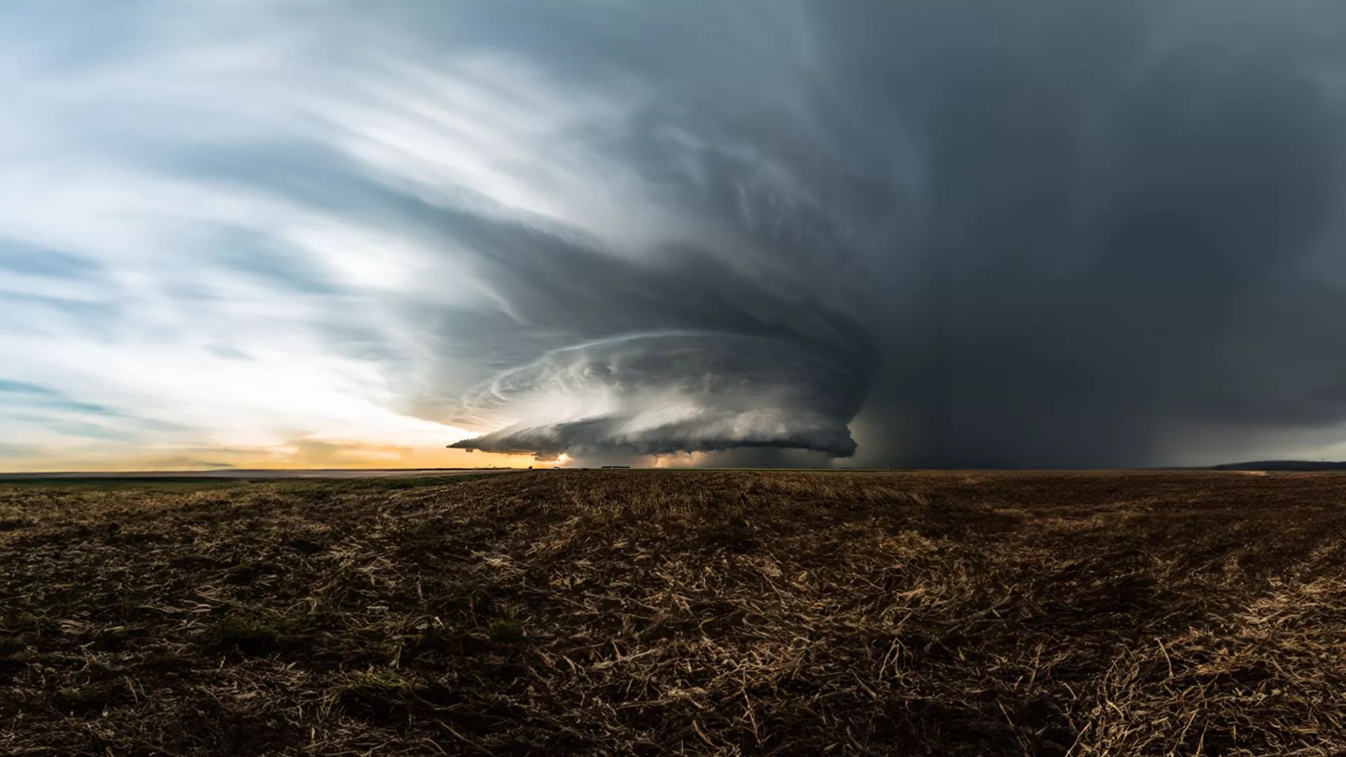 Photo of massive storm clouds and rain over a prairie
